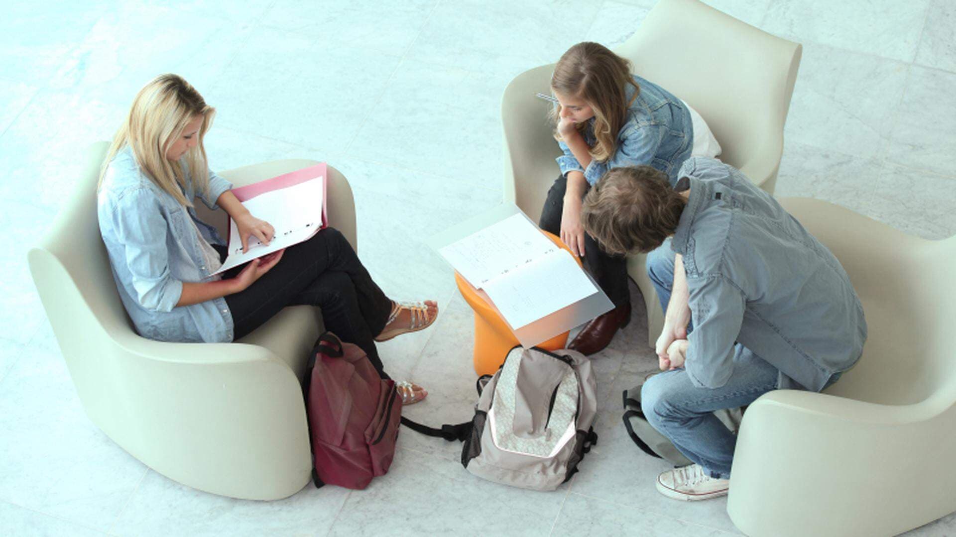 3 ungdomar som sitter i några fåtöljer och arbetar